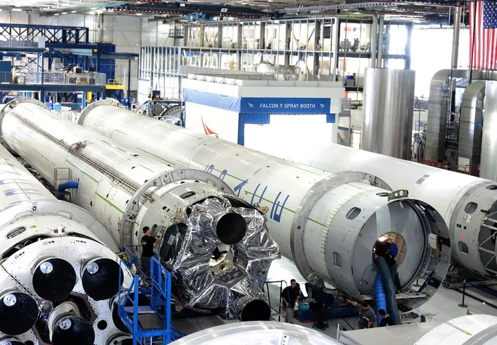 Rocket stages lying side by side on stands in a bright assembly hall